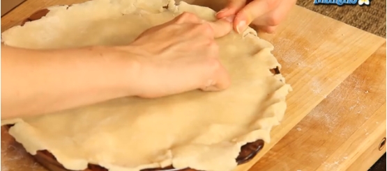 Press by fingers the edges of  the top layer of dough to edges form.
